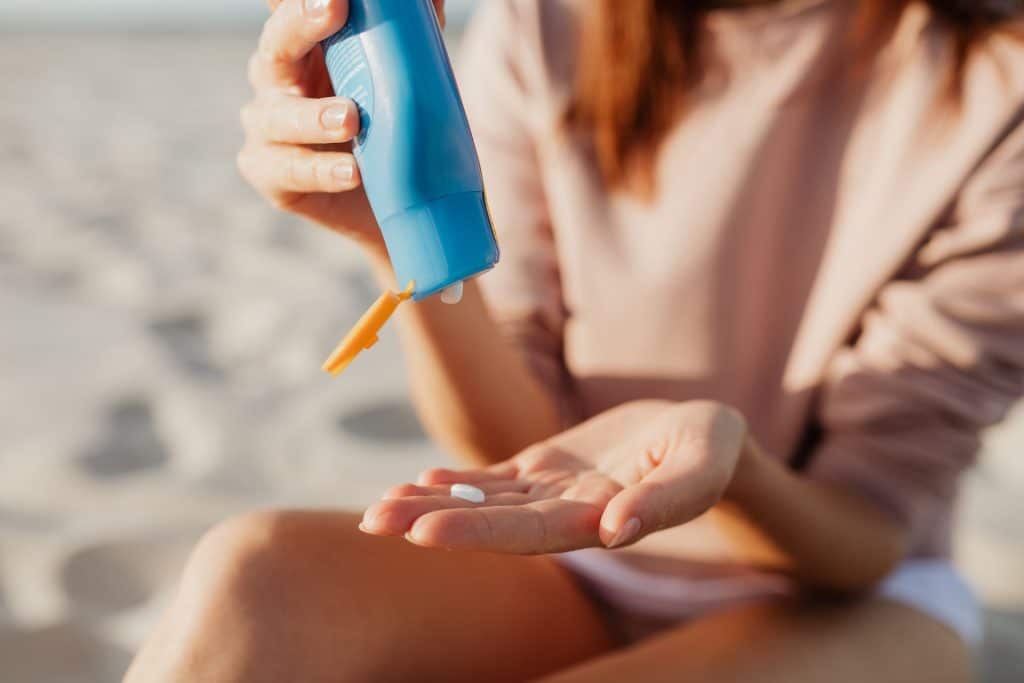 Eine Person trägt Sonnencreme am Strand an einem sonnigen Tag auf.